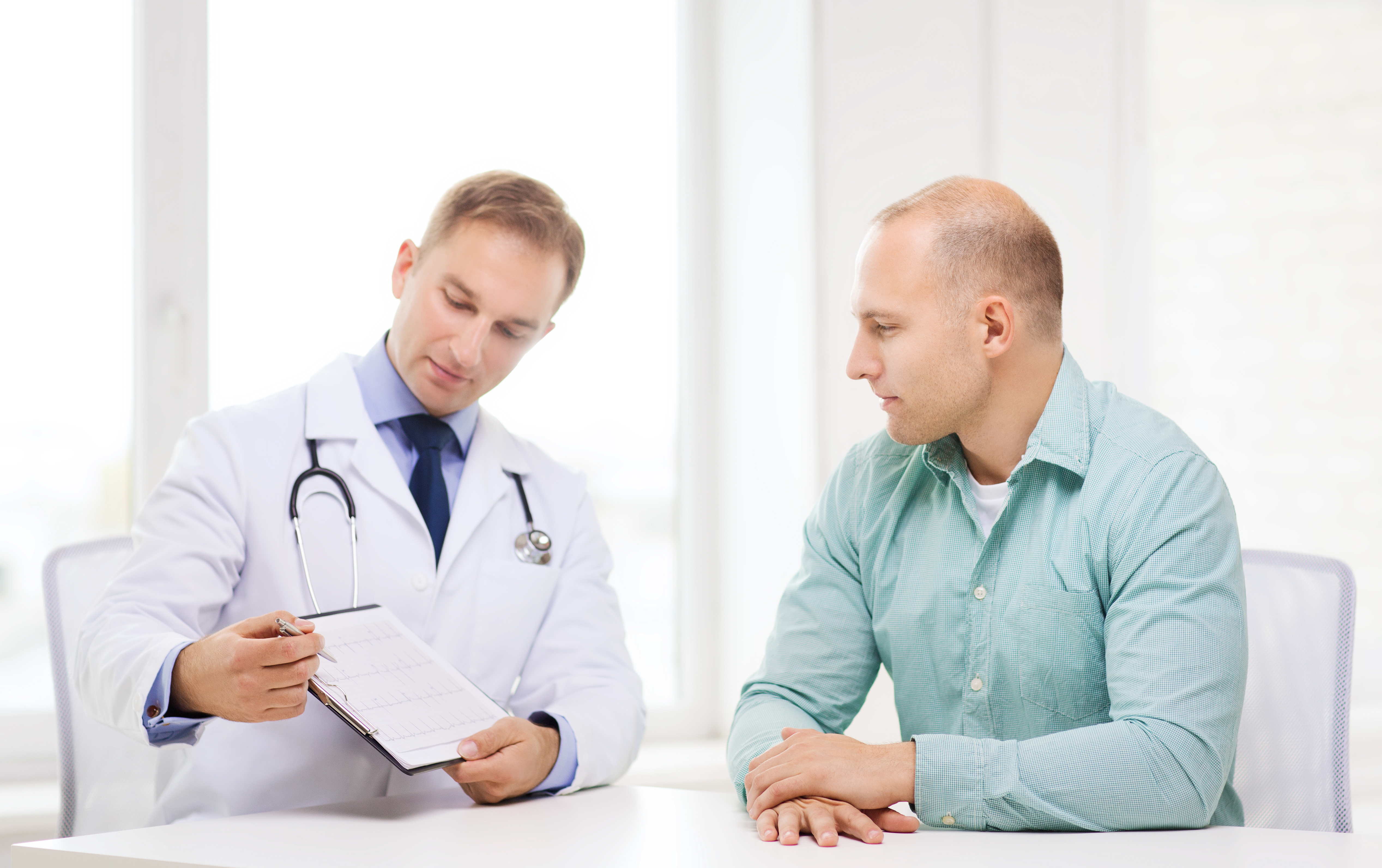 healthcare and medicine concept - serious doctor with clipboard and patient in hospital